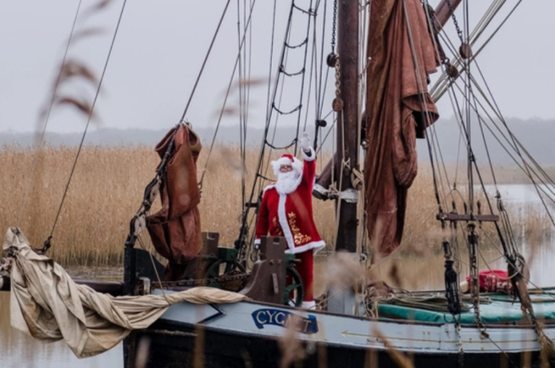 Father Christmas on a boat, with reeds in the background