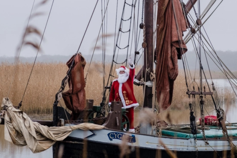 Father Christmas on a boat, with reeds in the background