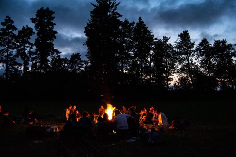 A group of people sat around a campfire at night