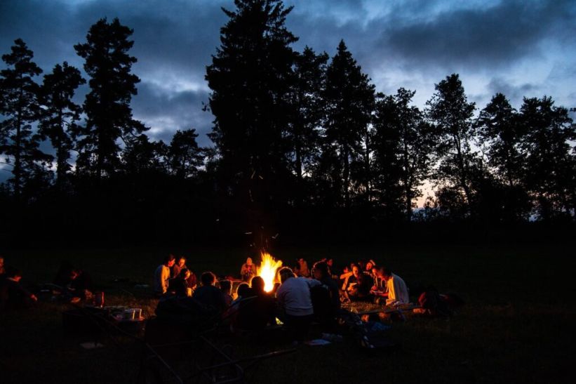 A group of people sat around a campfire at night