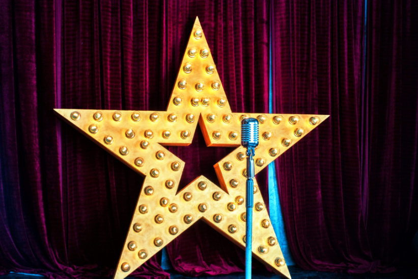 A star with a microphone and red curtains as the background