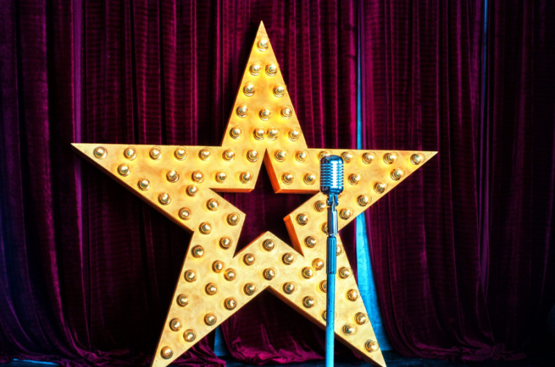 A star with a microphone and red curtains as the background