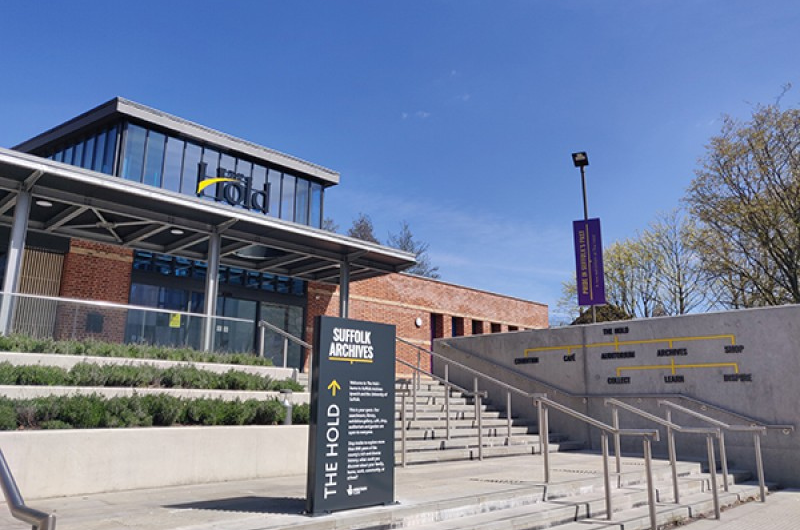 The Hold building with a blue sky. A sign reads 'Suffolk Archives.'